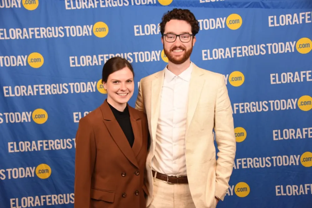 Skyler and his partner dressed up at the Big Brothers Big Sisters annual fundraising gala, in front of an EloraFergusToday backdrop.
